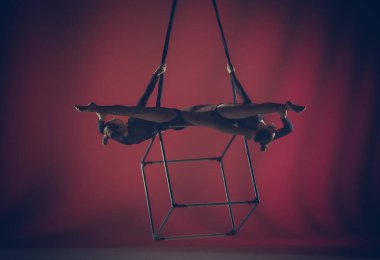 Modern koreografi ve akrobasi yaratıcı reklam konsepti. Kırmızı arka planda izole edilmiş kadın akrobatların portresi. Kız akrobatlar havada iplerle dönen dansçılar..