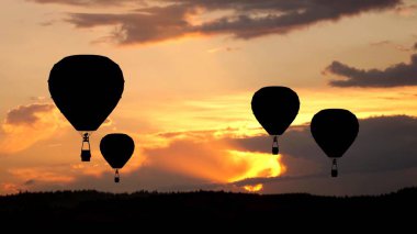 Ekolojik ulaşım reklam kavramı. Sıcak hava balonlarının silueti güneş batarken ve inerken. Gökyüzünde uçan bir sürü büyük hava balonuyla birlikte güzel batan güneş..