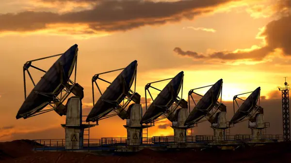 Modern industrial radio technology advertisement concept. Silhouettes of radar antennas receivers on the ground in the mountains against sunset sky. Few of large satellite stations in the field.