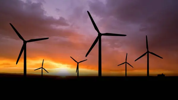Alternative energy and eco technology creative advertisement concept. Silhouettes of windmills against sunset sky in the land. Shot of many wind turbines with blades in field.