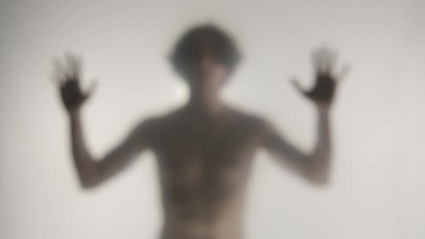 冷やされたカーテンやガラスの後ろに裸のトーソを持つ男のぼやけたシルエット 男は手のひらでガラスに触れ それに対して頭を打つ ゴーストとスピリッツのコンセプト Hdr Bt2020 Hlg — ストック動画