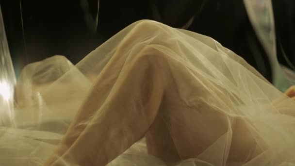 一个女人的腿被网状织物覆盖在阳光下 在黑色的背景上 一个女人躺在镜子里的模糊的倒影 慢动作 — 图库视频影像