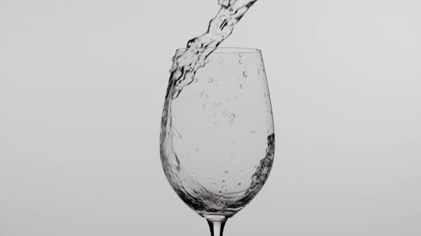 饮料创意广告的概念 在工作室用白色背景隔离的水滴近距离拍摄高脚杯 白葡萄酒或水从瓶子中倒入酒杯中产生波浪 — 图库视频影像