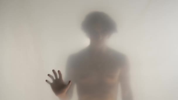 半身像在透明的结霜窗帘或玻璃窗后面有一个裸体躯干的男性侧影一个男人正把手放在窗帘的表面上 Hdr Bt2020 Hlg材料 — 图库视频影像