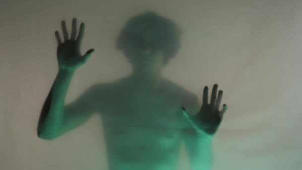 在绿色霓虹灯下 一个男人的模糊的轮廓 他的躯干光秃秃的在床垫幕后面 那个人正在摸着透明的障碍物 想挣脱出来 人类发展报告 关于鬼魂和鬼魂的概念 — 图库视频影像
