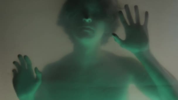 一个男人的模糊的轮廓 一个裸露的躯干在一个床垫幕后面 在绿色的霓虹灯关闭 那个人正在摸着透明的障碍物 想挣脱出来 鬼怪的概念和 — 图库视频影像