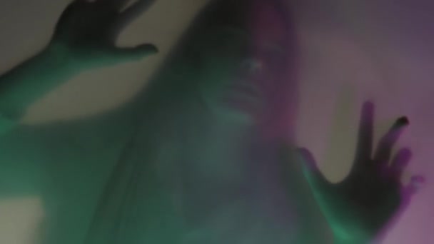 マットカーテンの背後にある女性の輝かしいシルエット ピンクと緑のネオンライトで 閉じます 女性が障壁に爪をかぶり それを引き裂こうとしています 幽霊と霊のコンセプト Hdr — ストック動画