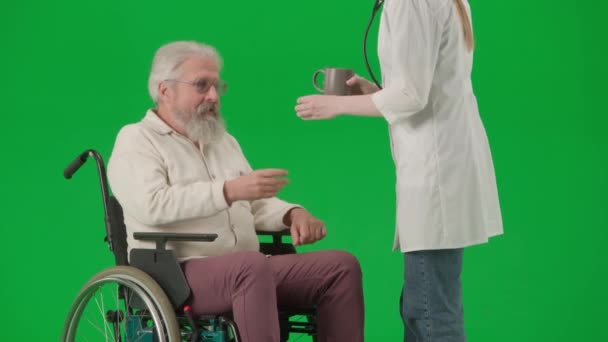 养恤金领取者照料和日常生活创意广告概念 彩色键绿色屏幕上的老年残疾人画像 坐轮椅的老人从女护士那里接过药品和水 — 图库视频影像
