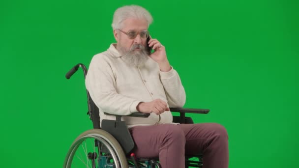 年金受給と日常生活クリエイティブ広告コンセプト クロマ グリーン スクリーンの老化した障害者の肖像画 車椅子に座ってスマートフォンで話すシニア男性 — ストック動画