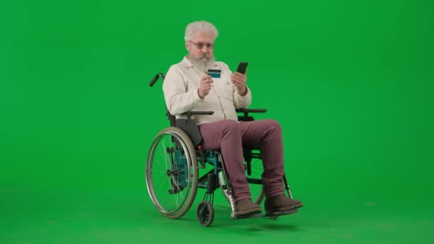 养恤金领取者照料和日常生活创意广告概念 彩色键绿色屏幕上的老年男子画像 坐轮椅的老人在智能手机上输入银行卡号码 上网购物 — 图库视频影像