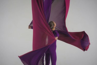 Modern koreografi ve akrobasi yaratıcı reklam konsepti. Stüdyoda beyaz arka planda izole edilmiş kadın akrobatın portresi. Hava ipeğiyle jimnastik yapan kız dansçı..