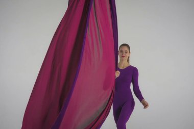 Modern koreografi ve akrobasi yaratıcı reklam konsepti. Stüdyoda beyaz arka planda izole edilmiş kadın akrobatın portresi. Hava ipeğiyle jimnastik yapan kız dansçı..