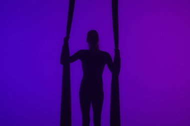 Modern koreografi ve akrobasi yaratıcı reklam konsepti. Renkli neon arka planda izole edilmiş kadın akrobat silueti. Hava ipeği üzerinde akrobatik hareketler yapan kız dansçı..