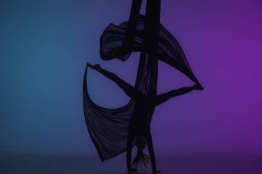 Modern koreografi ve akrobasi yaratıcı reklam konsepti. Renkli neon arka planda izole edilmiş kadın akrobat silueti. Hava ipeği üzerinde akrobatik hareketler yapan kız dansçı..