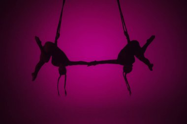 Modern koreografi ve akrobasi yaratıcı reklam konsepti. Pembe neon arka planda izole edilmiş iki kadın akrobatın silueti. Kızlar hava dansçıları ipler üzerinde uçan elementler sergiliyorlar..