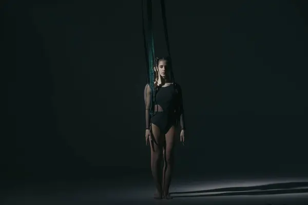 Modern choreography and acrobatics creative advertisement concept. Portrait of two female acrobats in studio isolated on black background. Girls aerial dancers performing element with ropes.