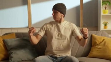Müzik ve insan duyguları yaratıcı reklam konsepti. Odada kanepede oturan bir gencin portresi. Kanepede oturan, kulaklıklı, müzik eşliğinde el sıkışan bir adam..