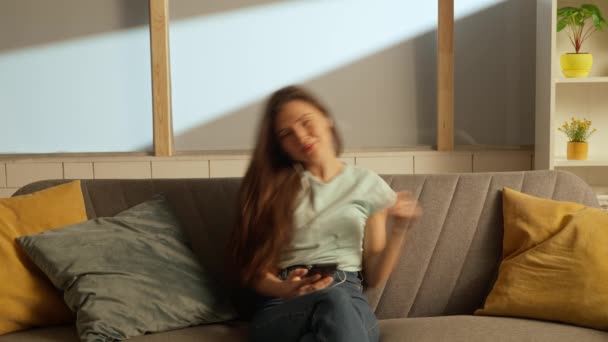 音楽と人間の感情クリエイティブ広告コンセプト ソファーに座っている部屋の若者の肖像画 イヤホンの女性は ソファーのリスニングミュージックに座って 歌の歌のラインを楽しんでいます — ストック動画