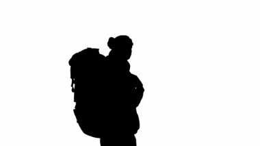 Sırtında büyük bir sırt çantası olan siyah bir gezgin silueti. Adam ayakta duruyor, etrafına bakıyor ve işaret parmağını yana çeviriyor. İzole edilmiş beyaz arkaplanda gezgin