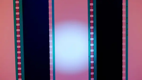 Two vertical film strips on a pink background with white circular light, close up. 35mm film slide frame. Long, retro film strip frame. Copy space