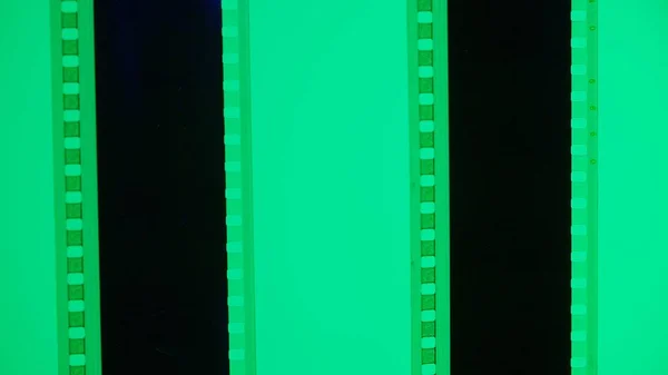 Two vertical film strips on a green background, close up. 35mm film slide frame. Long, retro film strip frame. Copy space