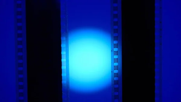 Two vertical film strips on a blue background with circular light, close up. 35mm film slide frame. Long, retro film strip frame. Copy space