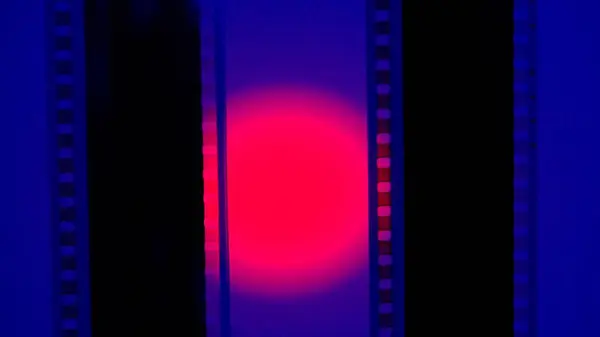 Two vertical film strips on a blue background with red circular light, close up. 35mm film slide frame. Long, retro film strip frame. Copy space