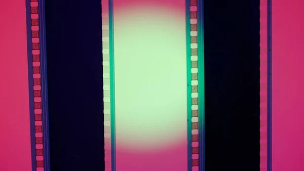 Two vertical film strips on a red background with green circular light, close up. 35mm film slide frame. Long, retro film strip frame. Copy space