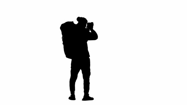 ハイキング中にカメラで写真を撮る男性旅行者の黒いシルエット 男性の旅行者は白い隔離された背景に立っています 旅行のコンセプト アクティブな休息 ハイキング リアビュー — ストック動画