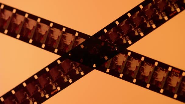 Дві Схрещені Смуги Фотоплівки Помаранчевому Рожевому Градієнтному Фоні Крупним Планом — стокове відео