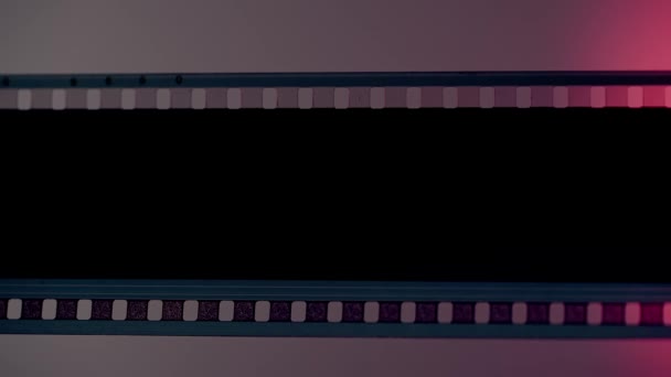 Порожня Нерозвинена Смуга Плівки Сірому Фоні Освітлена Рожевим Неоновим Світлом — стокове відео