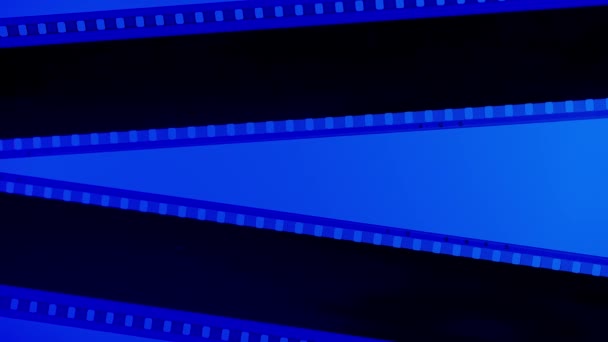 Duas Tiras Filme Preto Sobre Fundo Azul Iluminado Com Luz — Vídeo de Stock