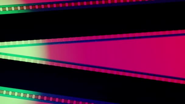 Två Svarta Filmremsor Rosa Bakgrund Belysta Med Grönt Neonljus Närbild — Stockvideo