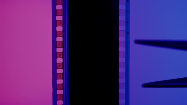 Ножиці Вирізають Смужку Фотоплівки Синьо Рожевому Фоні Крупним Планом — стокове відео