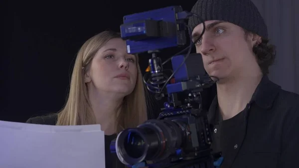 The crew backstage. A female producer and videographer views footage on a professional camera, close up