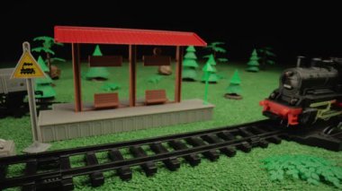 Yeşil arazinin ortasında yük vagonlu çocuk buharlı tren modeli. Çocuk sunumlarında ya da oyuncak reklamlarında kullanmak için ortam mükemmel.