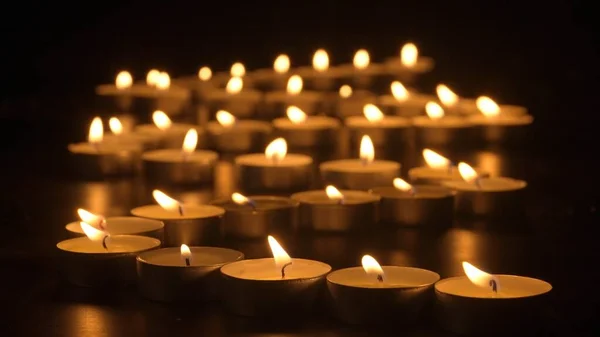 一排排的蜡烛在燃烧蜡烛在黑色的背景下燃烧 纪念日的概念 广告和设计项目的背景 — 图库照片