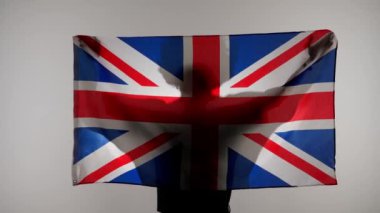 Ulusal bayrak vatansever reklam konsepti. Beyaz arka planda büyük bir bayrak taşıyan insan silueti. Büyük Britanya bayrağını elinde tutan bir adamın silueti.