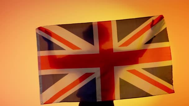 国旗爱国广告的概念 在黄色背景下高举大旗的人物形象 举着大不列颠国旗的人的轮廓 — 图库视频影像