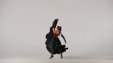 Modern koreografi bir dans. Beyaz arka planda dans eden kadın dansçı. Flamenko tarzı elbise giyen kadın stüdyoda elleri ve vücuduyla zarif İspanyol dansı hareketleri sergiliyor..