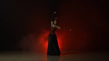 Modern koreografi bir dans. Kırmızı ışık ve dumanla siyah arka planda dans eden kadın. Kırmızı ve siyah elbiseli İspanyol dansçı flamenko koreografisinin unsurlarını gösteriyor.