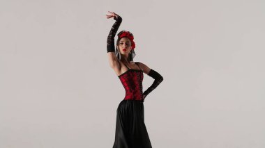 Modern koreografi bir dans. Beyaz arka planda dans eden kadın dansçı. Flamenko tarzı elbise giyen kadın stüdyoda elleri ve vücuduyla zarif İspanyol dansı hareketleri sergiliyor..
