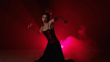 Modern koreografi bir dans. Kırmızı ışık ve dumanla siyah arka planda dans eden kadın. Kırmızı ve siyah elbiseli İspanyol dansçı flamenko koreografisinin unsurlarını gösteriyor.
