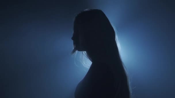 照明コンセプトのシルエット スタジオの黒いスモーキーな背景に明るいストロボライトに対する女性モデル 暗闇に光の光に囲まれた女性のシルエット サイドビュー — ストック動画
