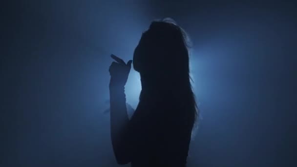 照明コンセプトのシルエット スタジオの黒い背景の明るいライトに対する女性モデル 女性プロフィール 暗闇の光線に囲まれたシルエットダンス — ストック動画