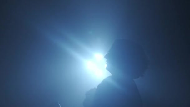 照明コンセプトのシルエット スタジオの黒い背景の明るいライトに対する男性モデル 暗闇に光の光に囲まれたマンクラバーシルエットダンス — ストック動画