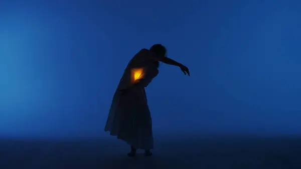 当代实验舞蹈概念 在演播室里表演的女舞蹈演员 年轻女子在黑暗的演播室里跳舞 衣服下面的胸膛里闪烁着温暖的光芒 — 图库照片