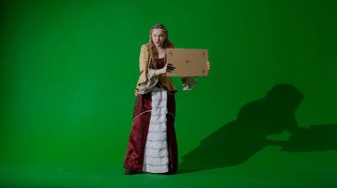 Tarihsel kişi modern yaşam tarzı reklamı. Krom anahtar yeşil ekran arka planda antik kıyafetli bir kadın. Rönesans elbisesi giymiş kadın elinde karton levha ve protesto sloganı taşıyor..