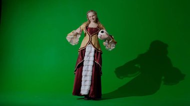 Tarihsel kişi modern yaşam tarzı reklamı. Krom anahtar yeşil ekran arka planında eski giysili bir kadın. Rönesans tarzı elbiseli bir kadın futbol topu gülümsemesi tutuyor..
