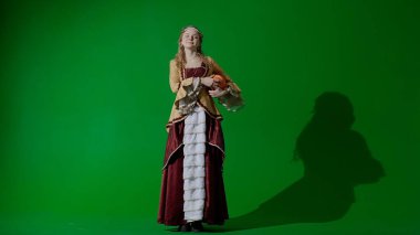 Tarihsel kişi modern yaşam tarzı reklamı. Krom anahtar yeşil ekranda eski bir kıyafet giymiş kadın. Rönesans tarzı elbiseli bir kadın Amerikan futbol topu gülüşü taşıyor..